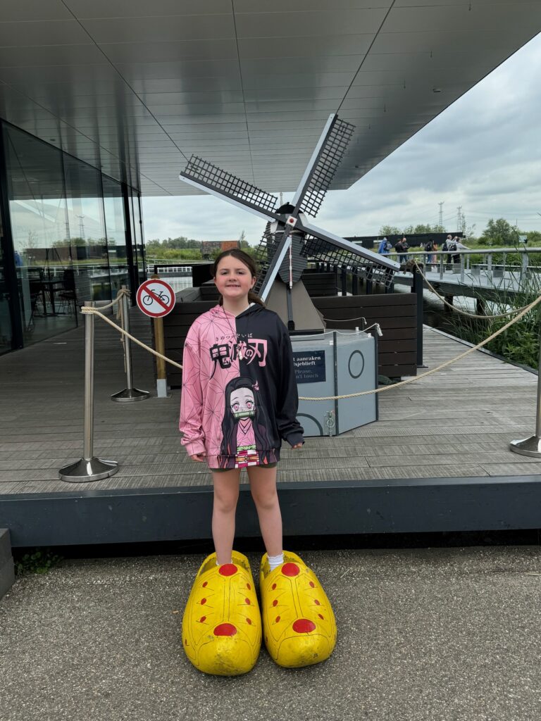 A girl in the classic Dutch wooden clogs in front of a windmill